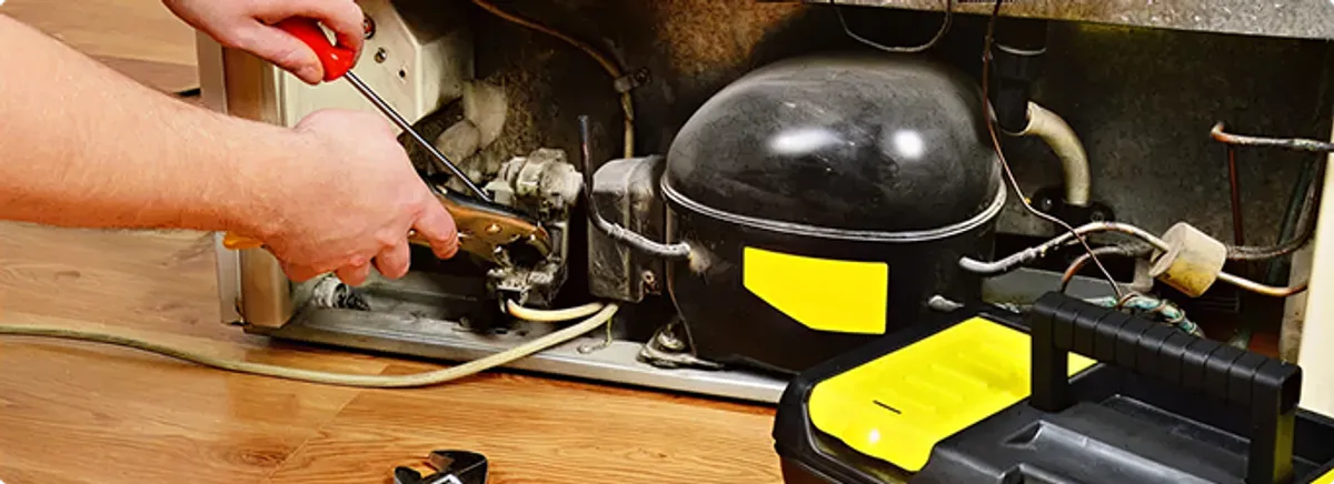 Refrigerator repair technician fixing the compressor and wiring in Albuquerque, NM